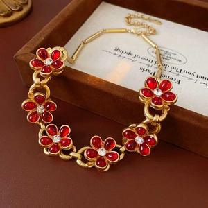 Macro view of vintage gold chain with red floral gemstone charms in a brown velvet box