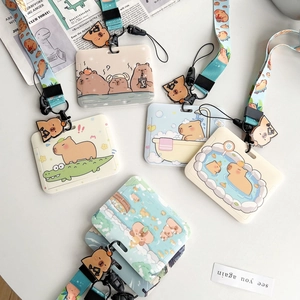 Flat lay of cute Capybara ID card holders with lanyards and pendants on a desk