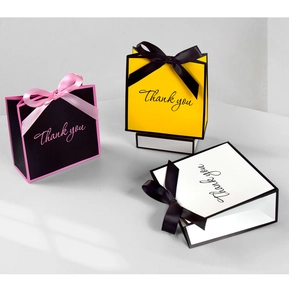 Detailed view of mini gift bags in black, yellow and white with silk ribbon bows