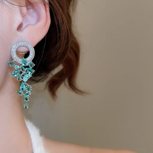 Détail macro de boucles d'oreilles pendantes en argent avec zircons bleus sur un mannequin