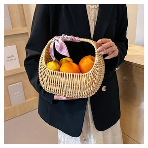 Detail of hand-woven wicker basket bag decorated with a pink silk scarf on the handle