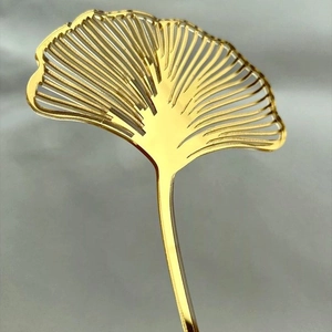 Golden acrylic ginkgo leaf cake topper with mirror finish for elegant birthday party decor