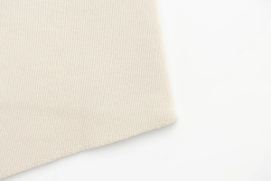 Gros plan sur la texture du tricot beige montrant les détails des coutures et du tissu