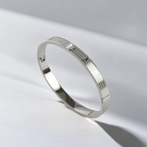 Close-up of titanium steel oval bangle with engraved musical notes and staff pattern