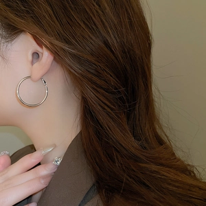 Close-up of classic silver hoop earrings with smooth metallic finish on a model
