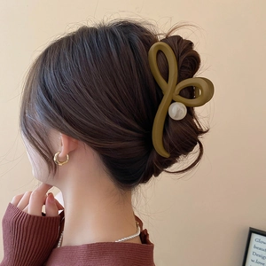 Détail d'une pince à cheveux marron avec perles blanches portée par un mannequin