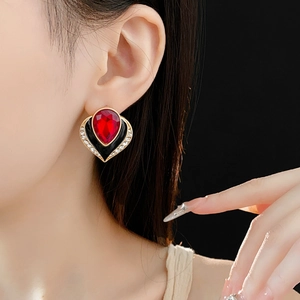 Detail of vintage heart earring with red gemstone and black enamel on a model