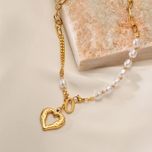 Collana a catena dorata con mezze perle e ciondolo a cuore vuoto su una pietra