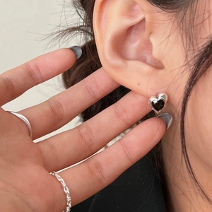 Close-up of minimalist heart-shaped black zircon earrings in 925 silver on ear