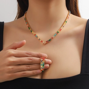 Macro detail of V-shaped golden necklace and ring with colorful cubic zirconia