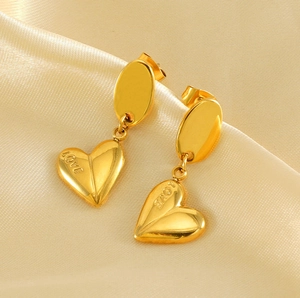 Detailed macro shot of gold heart earrings with LOVE engraving on silk background