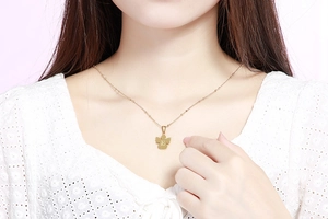 Dettaglio di una collana in acciaio inossidabile dorato con ciondolo lettera E e perline