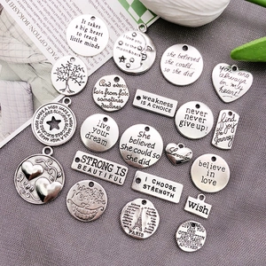 Macro shot of silver alloy charms with inspirational quotes and geometric shapes