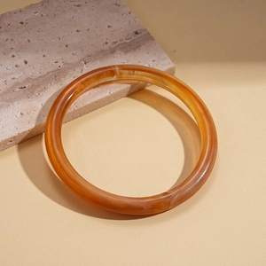 Detailed macro view of an amber acrylic bangle showing smooth texture and marble patterns