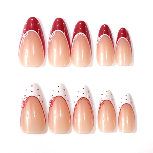 Detail of almond-shaped press-on nails with red and white French polka dot bow designs