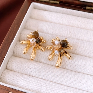 Detailed close-up of 18K gold plated tiger eye earrings in a beige velvet jewelry box