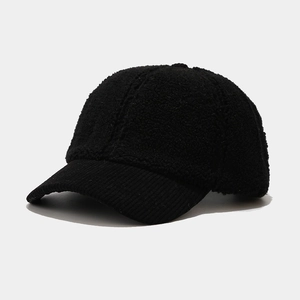 Close-up of black lamb wool and corduroy patchwork on a warm winter baseball cap
