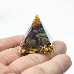 Detailed view of a 3cm amethyst resin pyramid held by hand with crystal gravel and gold flakes