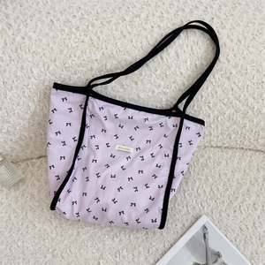 Dettaglio della borsa tote lilla con motivi a fiocco neri ed etichetta logo
