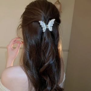 Dettaglio dell'elegante molletta a farfalla con zirconi e madreperla sui capelli