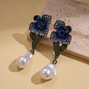 Detailed view of silver flower earrings with blue rhinestones and baroque pearls