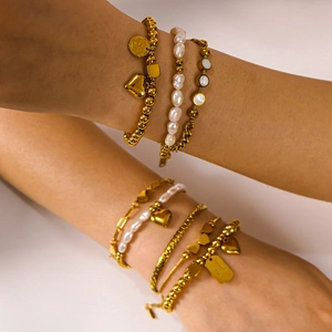Golden titanium steel chain bracelets with pearls and heart pendant on a model wrist