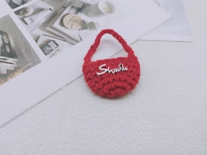 Dettaglio di una mini borsa rossa fatta a mano all'uncinetto con logo metallico argento