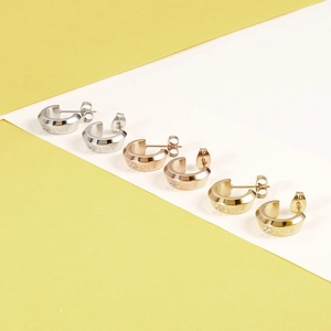 Detailed macro view of three pairs of stainless steel love earrings in gold, silver, and rose