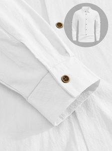 Close-up of white linen shirt fabric texture and buttoned cuff detail on casual beach top