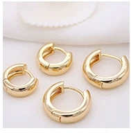 Macro view of gold hoop earrings in four different sizes on white fabric texture