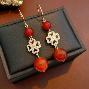 Detailed close-up of vintage earrings with red agate beads and golden clover charms