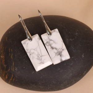 Detail of rectangular drop earrings with white marble texture and silver metal hooks
