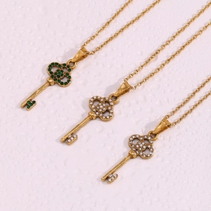 Detail of gold hollow key pendants with sparkling green and white cubic zirconia