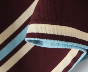 Macro shot of burgundy piqué fabric with white and sky blue stripes and fine stitching