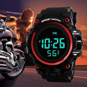 Macro shot of large digital sports watch with red bezel and black strap in outdoor scene