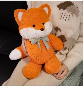 Close-up of orange plush fox toy with blue checkered bow on soft teddy fleece texture