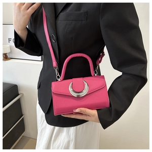 Sac à main rose fuchsia à texture litchi et fermoir croissant porté par un mannequin