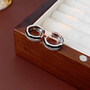 Macro shot of silver hoop earrings with black enamel stripes and micro-set zircon