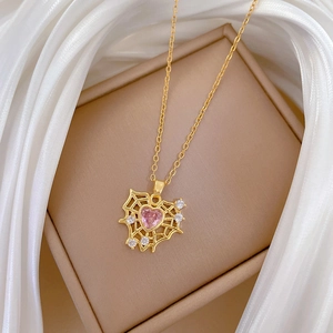 Gold heart spiderweb necklace with pink gemstone and diamonds on silk background