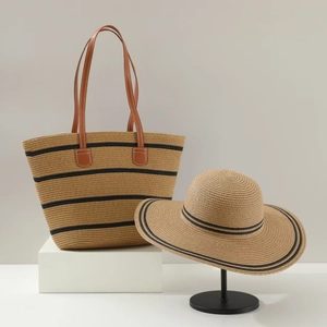 Detail of dark khaki straw tote bag and matching wide-brim hat with black ribbon decoration