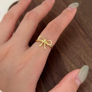 Close-up of elegant golden bow ring on finger with a minimalist polished silver design