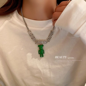 Détail d'un collier en chaîne argentée avec pendentif ours vert et lettres J'ADIOR