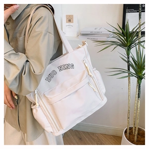Close-up of white canvas tote bag with side pockets and long shoulder straps for women