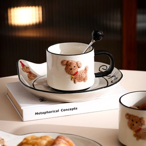 Detail of a cream ceramic coffee cup set with 3D teddy dog relief on a book