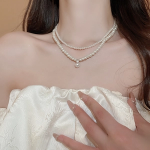 Detail shot of a double-layer pearl necklace with a zircon pendant on a female model