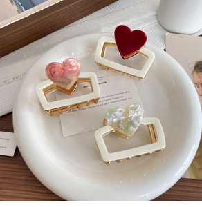Detailed close-up of 3-piece heart-shaped hair claws on a vintage ceramic plate