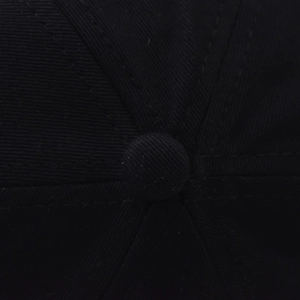 Macro shot of the black cotton baseball cap crown with stitch seams and top button detail