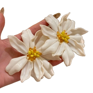 Handheld view of large white acrylic flower earrings with yellow beaded centers