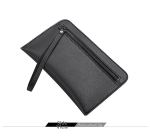 Detail view of the black textured leather clutch bag with a zipper pocket and wrist strap