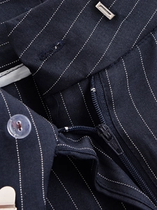 Détail de la taille du pantalon rayé avec bouton en résine et crochet métallique